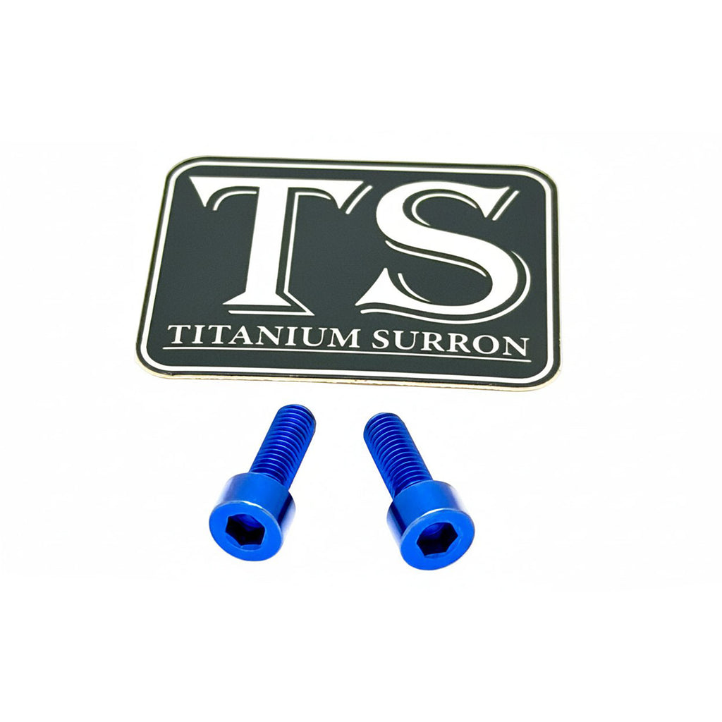 Two blue anodized hex head screws placed below a black rectangular badge with white lettering that reads 'TS TITANIUM SURRON' on a plain white background.
