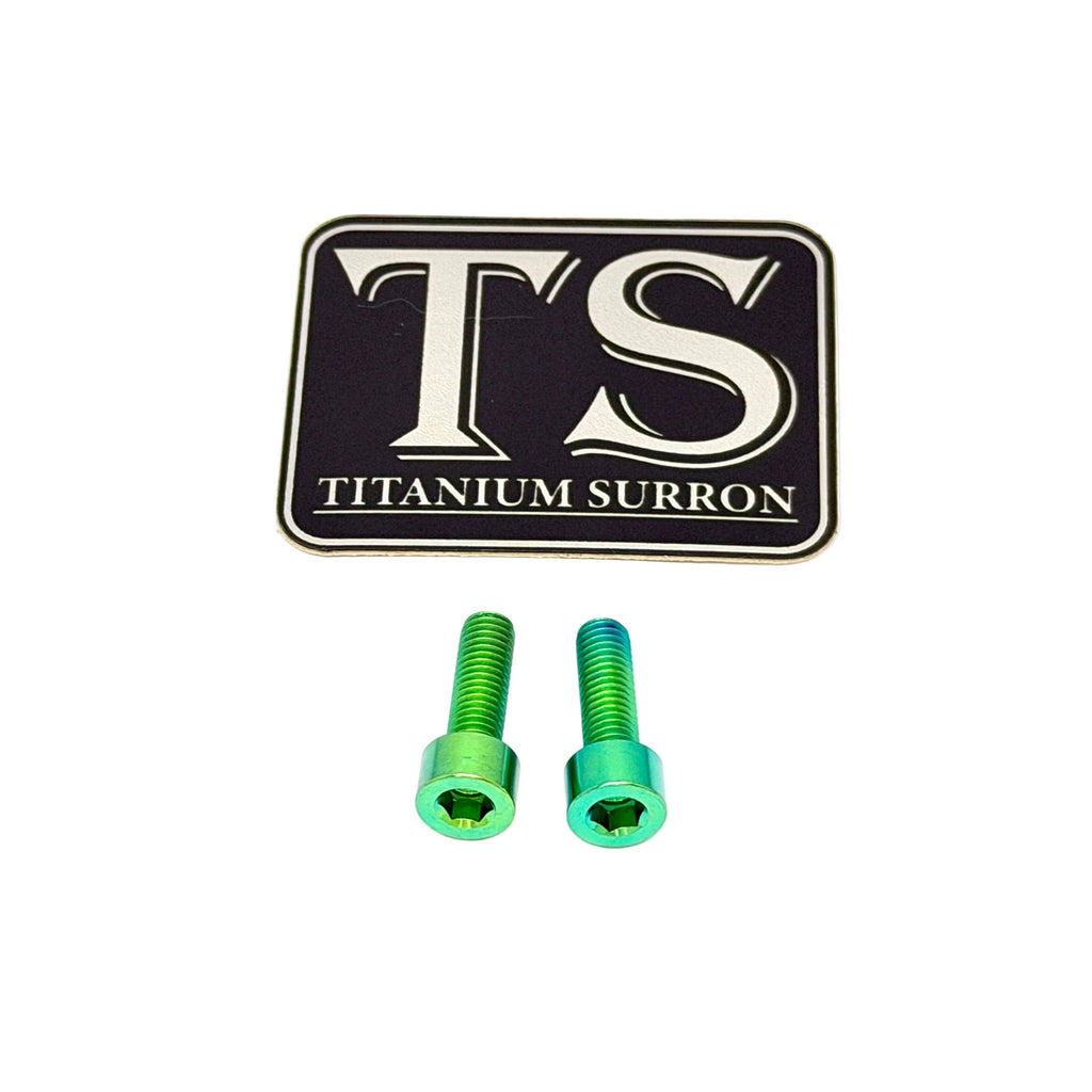 Two green titanium surron bolts with a black and silver 'TS TITANIUM SURRON' logo plaque, shown on a white background.