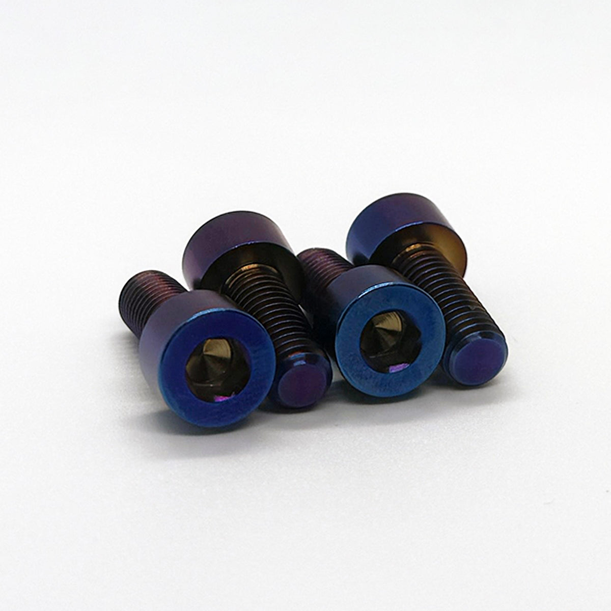 Four hex screws with iridescent blue and purple titanium finishes, arranged on a plain white background.