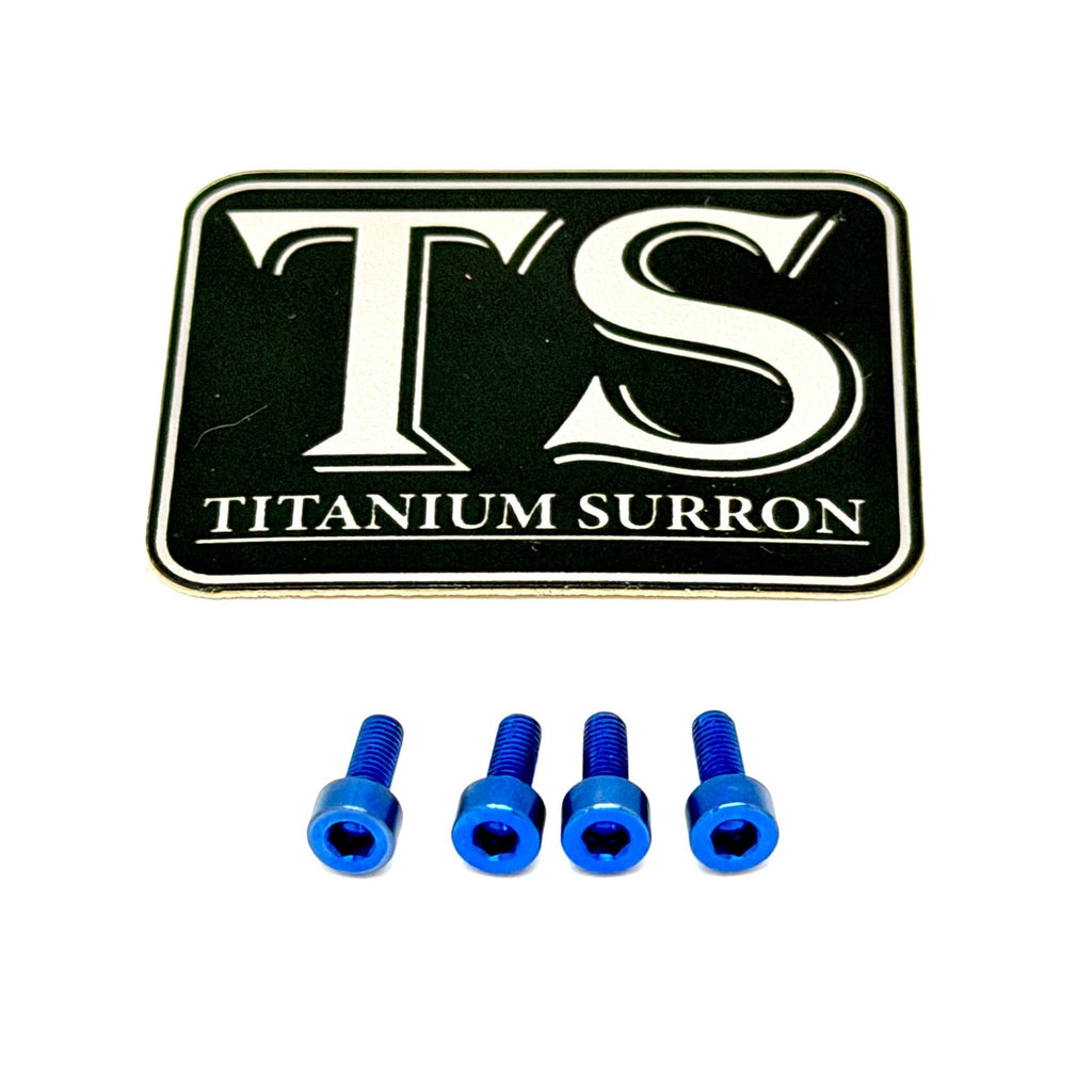 A black rectangular badge or emblem with white 'TS' lettering and the words 'TITANIUM SURRON' below, shown above four small bright blue hex screws on a plain white background.