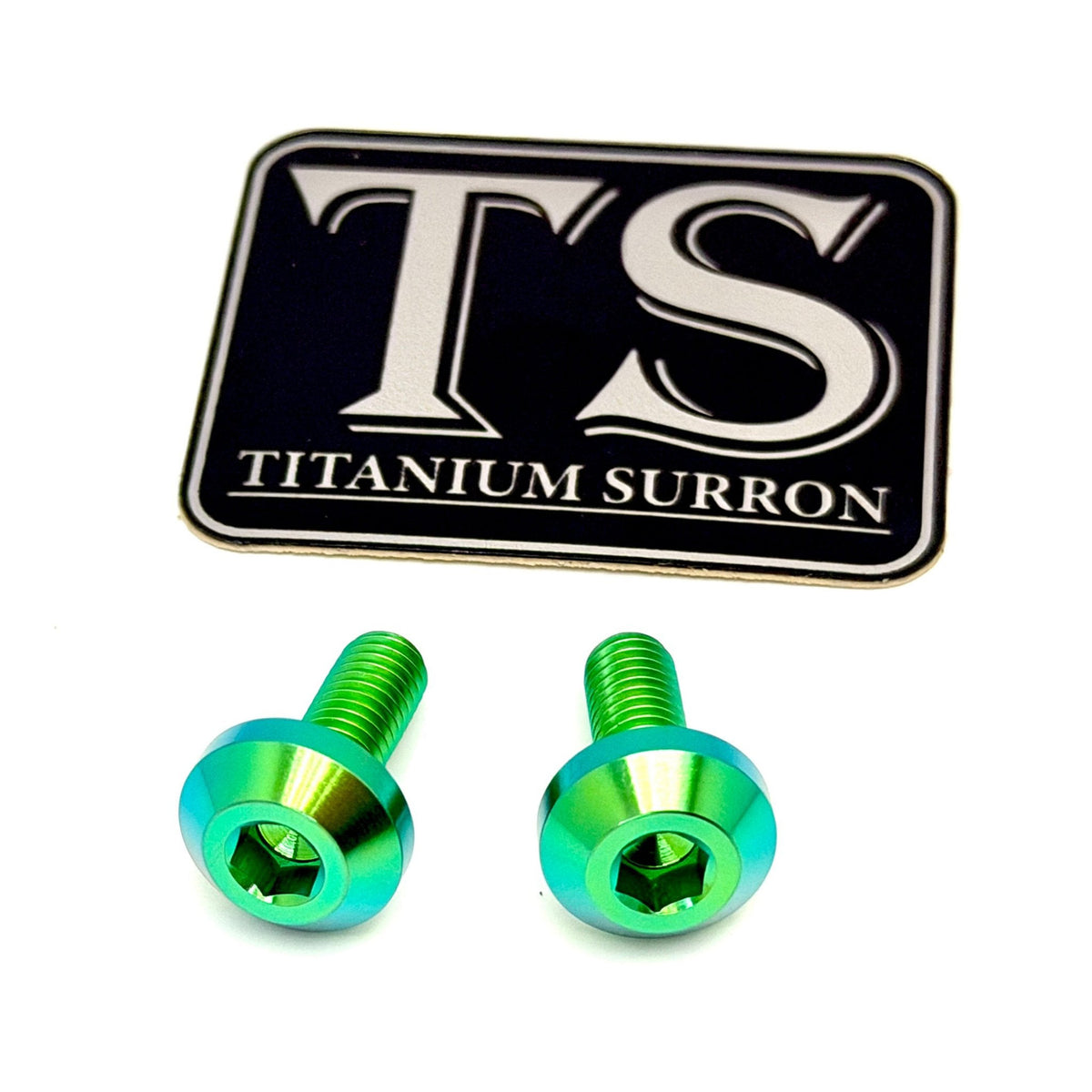 Two green metallic titanium surron screws with a black and silver TS Titanium Surron logo sticker on a white background.