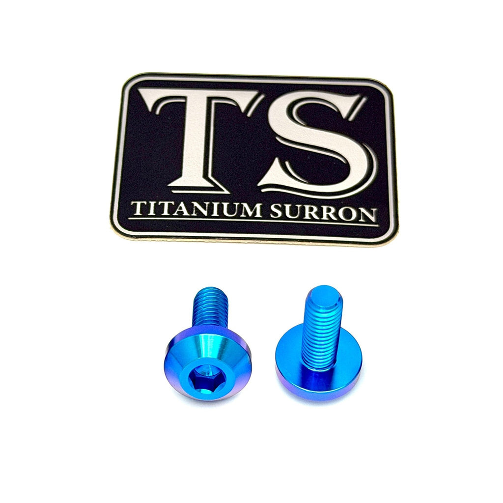 Two bright blue titanium screws with a hex socket head, displayed below a black and silver 'TS TITANIUM SURRON' logo patch on a white background.