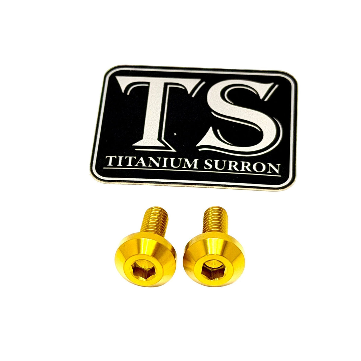 Two gold-colored titanium surron screws with a black and white TS Titanium Surron logo patch, shown on a plain white background.